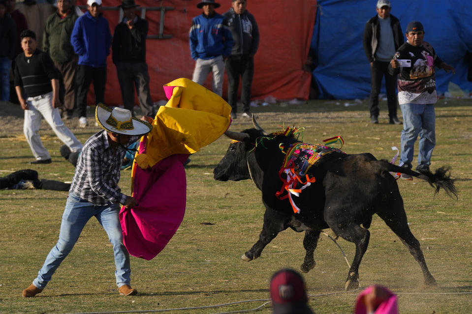 Un torero aficionado ondea el capote durante la festividad católica en honor de la Virgen del Rosario, en el pueblo andino de Huarina, Bolivia, el lunes 9 de octubre de 2023. Un grupo de novilleros aficionados alistas una actuación caricaturizada del toreo español, pero sin sacrificar a los toros. (AP Foto/Juan Karita)