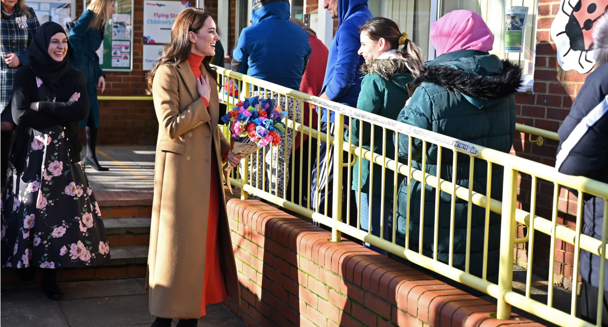 kate middleton wearing orange sweater and skirt and camel massimo dutti coat outside nursery school 