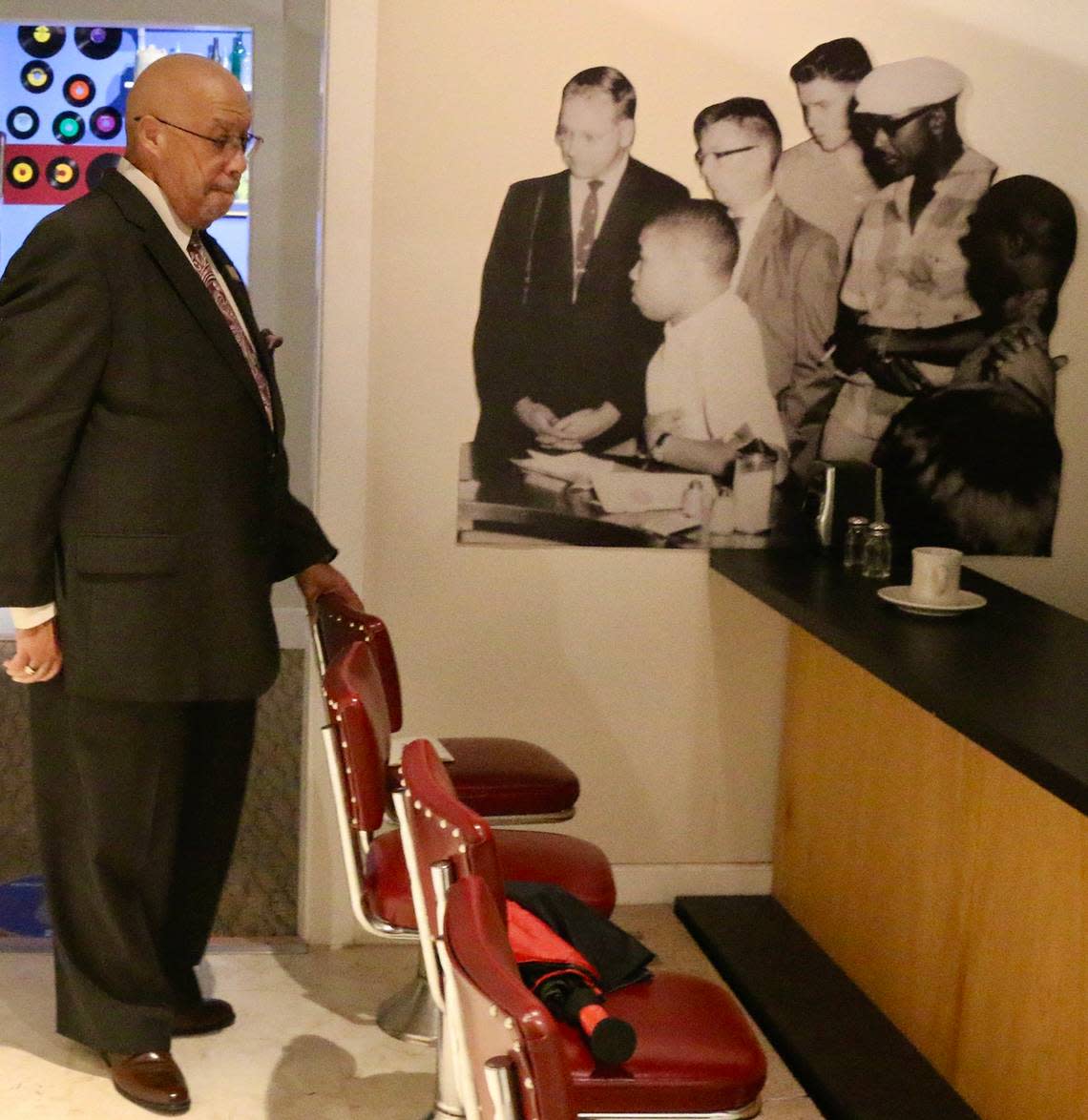 Rodney Hurst visits a replica of the lunch counter where he took part in a peaceful demonstration to protest the discrimination faced by Blacks, at a display at at the Ritz Theater, on Friday, Oct. 23, 2020, in Jacksonville, Fla. In the background is a blow up of a photo taken in 1960 when he was 16. After leaving the lunch counter in downtown Jacksonville as a teen, a mob of whites began indiscriminately clubbing African Americans with baseball bats and ax handles during a day now remembered as Ax Handle Saturday.