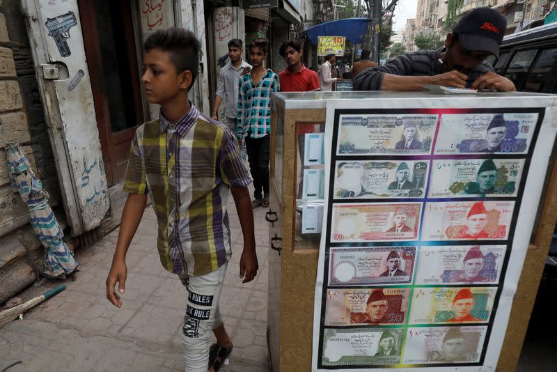FILE PHOTO: Boy walks past a sidewalk money exchange stall in Karachi