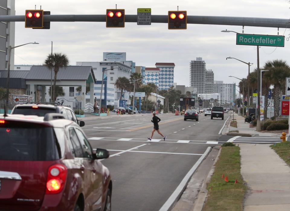 A pedestrian crosses State Road A1A, or Atlantic Avenue, at Rockefeller Drive, in a crosswalk using a pedestrian hybrid beacon, a new safety device installed by the Florida Department of Transportation earlier this year.