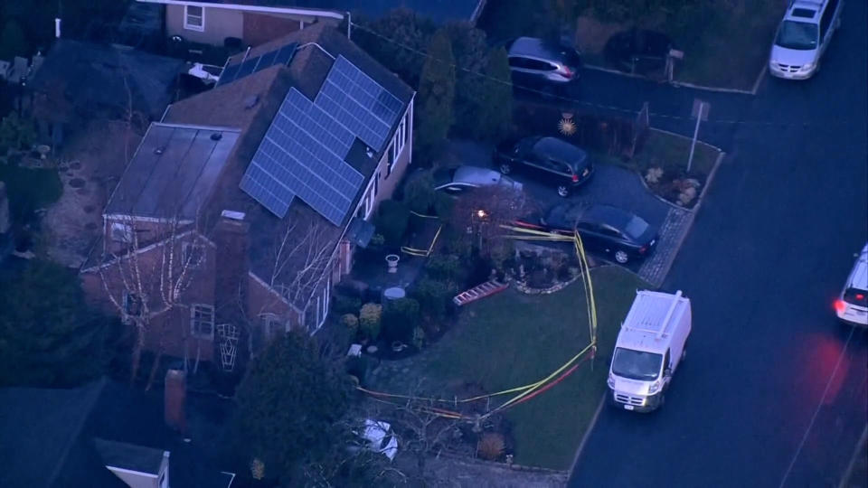 A house with solar panels is roped off with yellow caution tape and a sinkhole is visible next to the driveway (NBC New York)