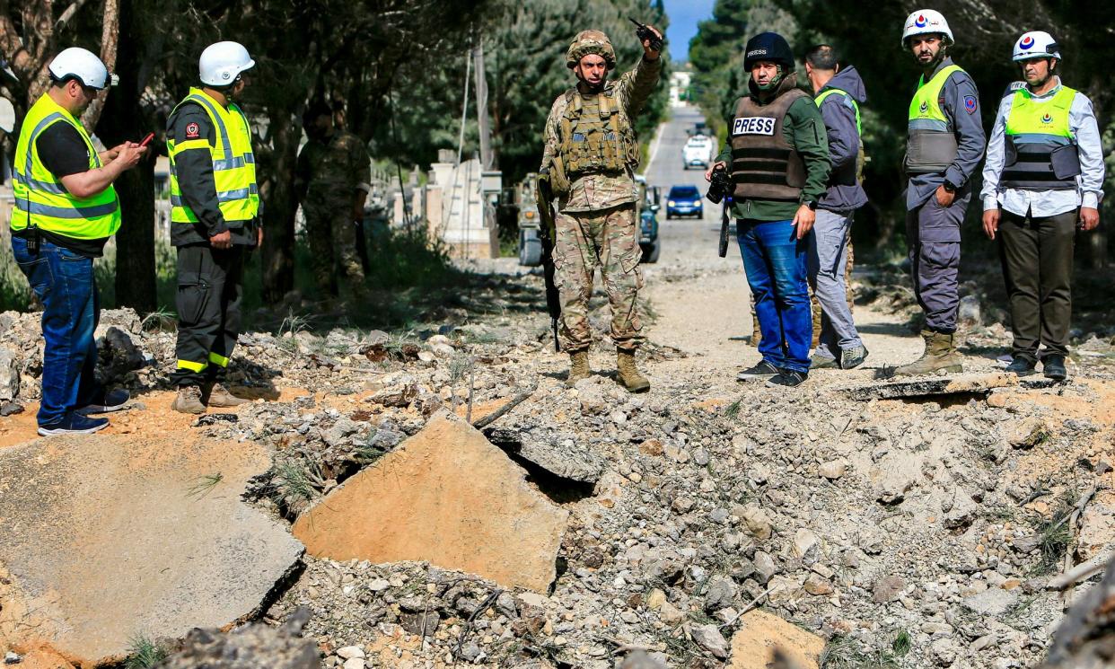 <span>A Lebanese soldier and emergency responders survey an impact crater after an Israeli airstrike hit a road in southern Lebanon on Monday.</span><span>Photograph: AFP/Getty Images</span>