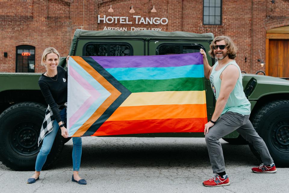 Hotel Tango Distillery owners Hilary and Travis Barnes pose with an LGTBQ+ Pride flag.