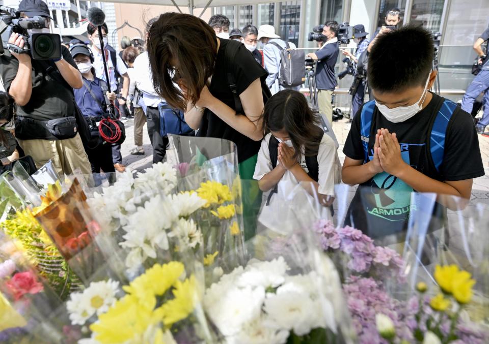 People offer prayers at a makeshift memorial near the scene where the former Prime Minister Shinzo Abe was fatally shot while delivering his speech to support the Liberal Democratic Party's candidate during an election campaign in Nara, Saturday, July 9, 2022. (Kyodo News via AP)