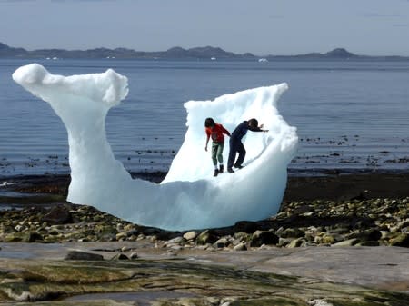 FILE PHOTO: Children play amid icebergs on the beach in Nuuk