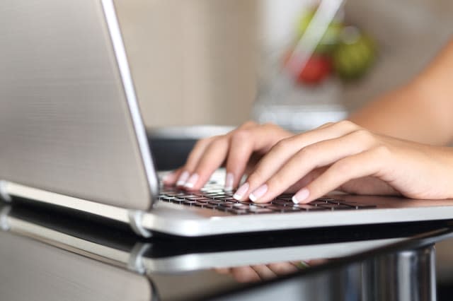 Woman hands working with a laptop at home