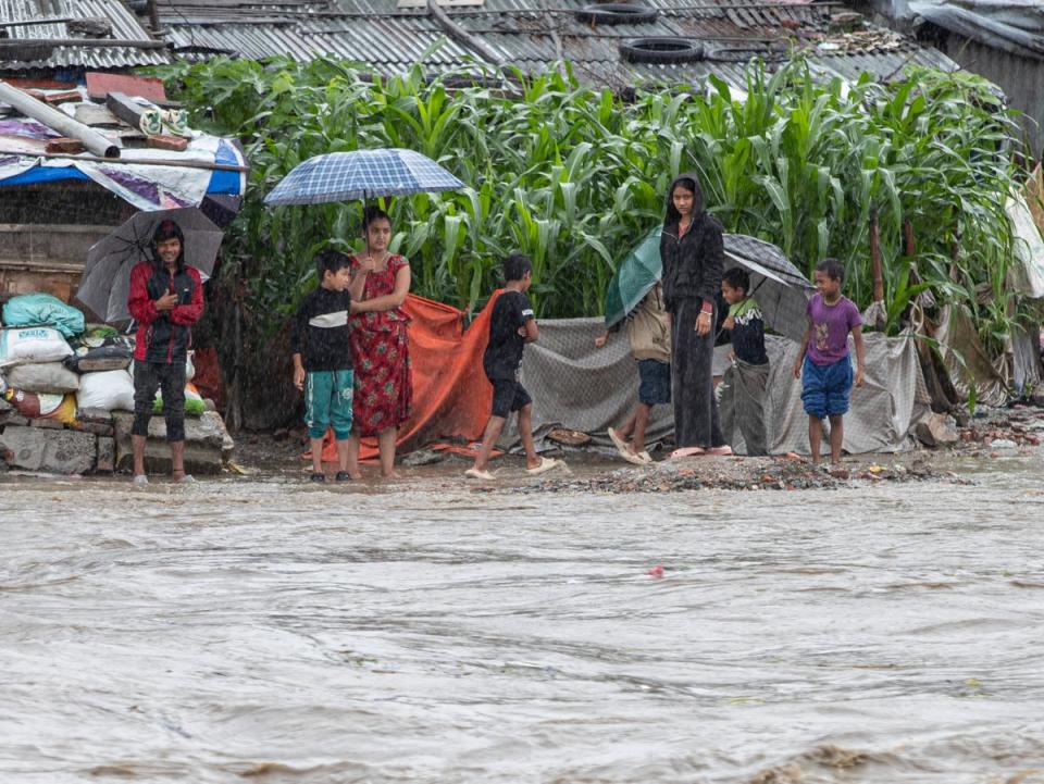Un grupo de personas busca refugio cerca de un templo inundado por la crecida del río Hanumante tras las lluvias torrenciales en Katmandú, Nepal (EPA)