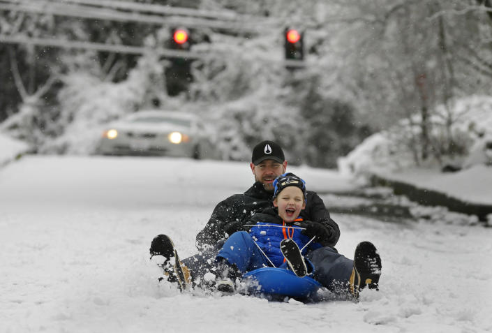 Tait Covert sleds with his son Aron, 6, on a hilly street in Seattle, Monday, Feb. 6, 2017. A snowstorm that blanketed Seattle and western Washington state into Monday morning prompted widespread school closures, flight cancellations and power outages. (AP Photo/Ted S. Warren)