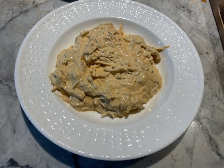 Light-orange Buffalo-chicken dip on a white plate. The dip has visible shreds of chicken mixed in