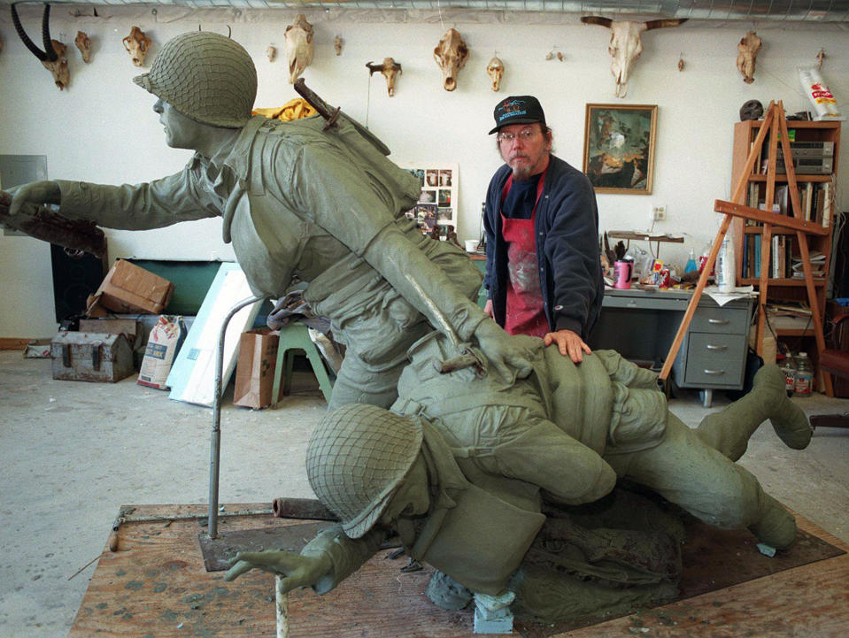 In this November 1998 photo Kansas sculptor Jim Brothers stands in his Lawrence, Kan., studio with "Across the Beach," one of several bronze sculptures he has created for National D-Day Memorial in Bedford, Va. Brothers, whose works are part of historical monuments around the country, died Tuesday, Aug. 20, 2013, at his home in Lawrence where he had been in hospice care, according to a funeral director at Warren McElwain Mortuary. He was 72. (AP Photo/Lawrence Journal World, Mike Yoder)