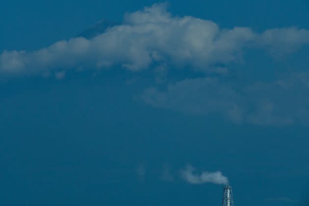 Mount Fuji and a factory chimney seen from the Tokaido Shinkansen (bullet train).