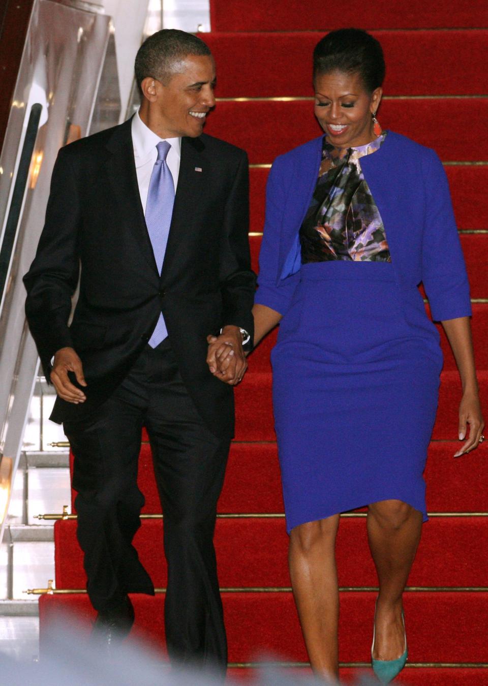 President Barack Obama and first lady Michelle Obama land in England in 2011. Michelle wears a purple suit.