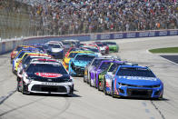 Christopher Bell (20) and Kyle Larson (5) lead the field into Turn 1 on a restart during the NASCAR Cup Series auto race at Texas Motor Speedway in Fort Worth, Texas, Sunday, April 14, 2024. (AP Photo/Larry Papke)