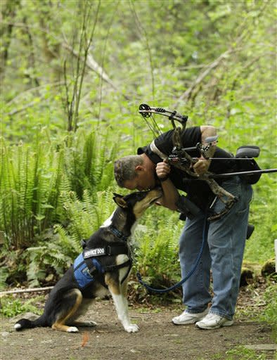 U.S. Army Spc. Mike Ballard kisses Apollo, his service dog, during a break in an archery shooting session, Friday, May 17, 2012, in Puyallup, Wash. Ballard says his dog helps him get through the worst symptoms of the post-traumatic stress disorder that is a remnant of an explosion in Afghanistan that ended his career as an Army medic. (AP Photo/Ted S. Warren)