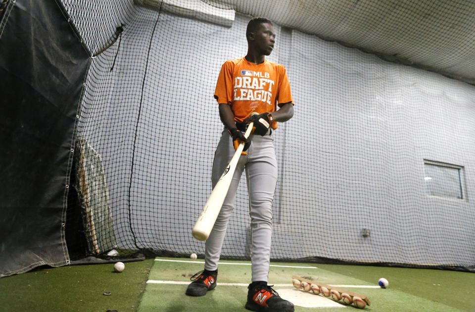 Frederick Keys catcher Dennis Kasumba warms up in a batting cage before the team's baseball game against the Trenton Thunder, Tuesday, July 4, 2023, in Trenton, N.J. Kasumba, from Uganda, dreams of reaching the major leagues someday. The 19-year-old catcher had a chance to play for the Frederick Keys of the MLB Draft League this past month. (AP Photo/Noah K. Murray)