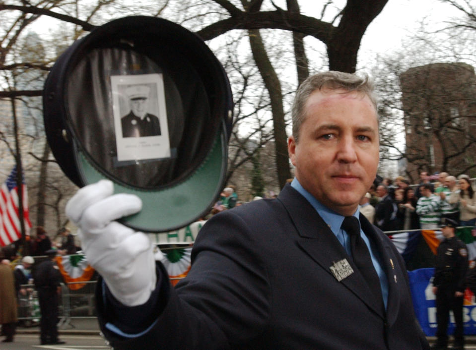 FILE - In this Saturday, March 16, 2002 file photo, firefighter Dan Walker displays a photo of Father Mychal Judge taped inside his hat during the 241st St. Patrick's Day Parade in New York. Judge, the Catholic chaplain of the New York City Fire Department, was killed in the Sept. 11 attacks on the World Trade Center. (AP Photo/Chad Rachman, File)