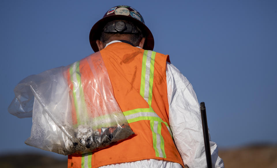 Huntington Beach, CA - October 05: An environmental oil spill cleanup crew member wears a hot protective suit on a hot day as he walks the beach, loading chunks of oil off the beach from a major oil spill in Huntington Beach Tuesday, Oct. 5, 2021. Environmental cleanup crews are spreading out across Huntington Beach and Newport Beach to cleanup the damage from a major oil spill off the Orange County coast that left crude spoiling beaches, killing fish and birds and threatening local wetlands. The oil slick is believed to have originated from a pipeline leak, pouring 126,000 gallons into the coastal waters and seeping into the Talbert Marsh as lifeguards deployed floating barriers known as booms to try to stop further incursion, said Jennifer Carey, Huntington Beach city spokesperson. At sunrise Sunday, oil was on the sand in some parts of Huntington Beach with slicks visible in the ocean as well. We classify this as a major spill, and it is a high priority to us to mitigate any environmental concerns, Carey said. Its all hands on deck. (Allen J. Schaben / Los Angeles Times via Getty Images)