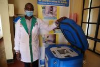 Clinical officer Gerald Yiaile stands next to empty vaccine refrigerator at health clinic, in Sekenani
