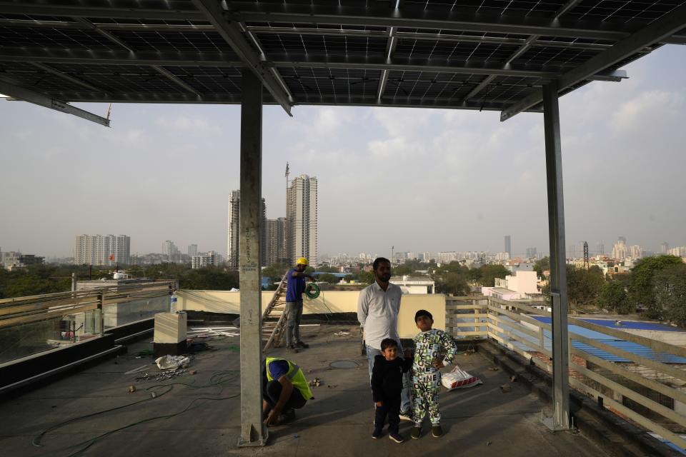 Children along with their father look at the newly installed solar panels on the roof of their house in Gurugram on the outskirts of New Delhi, India, Tuesday, Feb. 20, 2024. India is renewing its push to add rooftop solar to meet the needs of a fast-growing nation that's hungry for energy. (AP Photo/Manish Swarup)