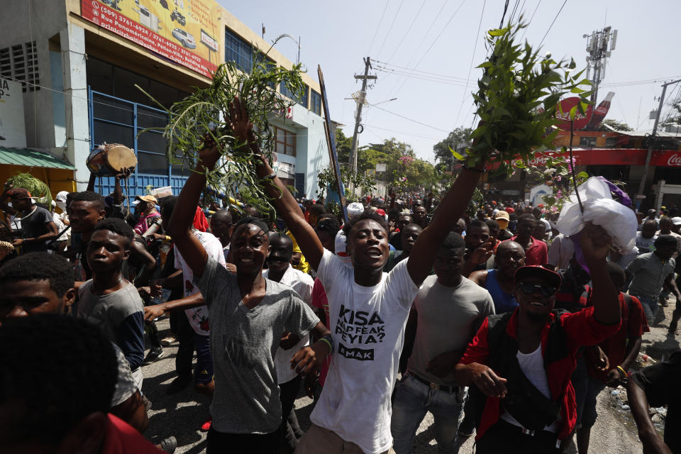 Demonstrators march during an anti-government protest in Port-au-Prince, Haiti, Friday, Oct. 11, 2019. Protesters burned tires and spilled oil on streets in parts of Haiti's capital as they renewed their call for the resignation of President Jovenel Moïse just hours after a journalist was shot to death. (AP Photo/Rebecca Blackwell)