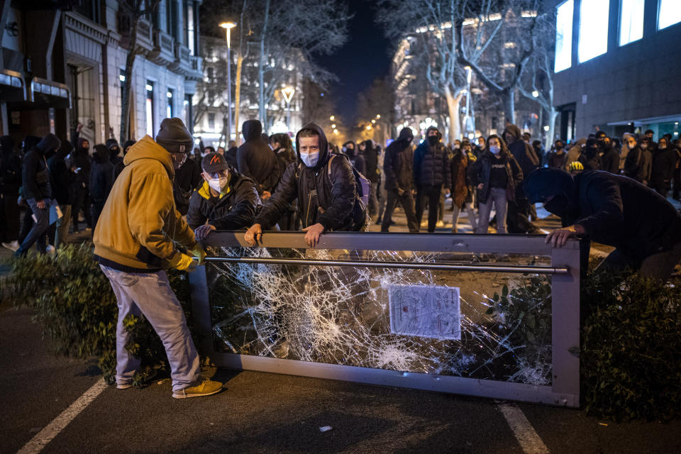 Demonstrators make barricades during clashes with police during a protest condemning the arrest of rap singer Pablo Hasel in Barcelona, Spain, Tuesday, Feb. 16, 2021. The imprisonment of Pablo Hasel for inciting terrorism and refusing to pay a fine after having insulted the country's monarch has triggered a social debate and street protests. (AP Photo/Emilio Morenatti)