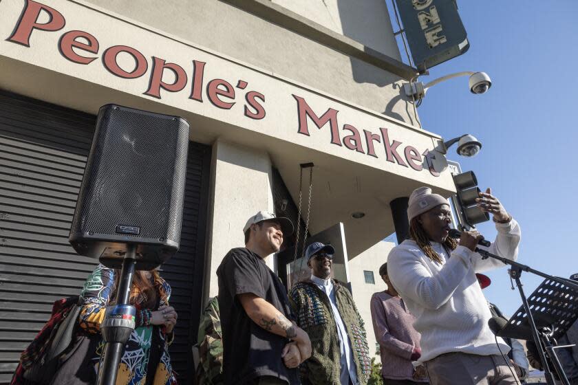 LOS ANGELES, - JANUARY 10: Pastor Stephen Jnmarie, right, of Creating Justice, LA speaks on Wednesday, Jan. 10, 2024 to announce the purchase of Skid Row People's Market from owner Danny Park, (center) and his family. Park decided to sell to Creating Justice, LA to keep ownership in the community, address food insecurity, maintain and provide community jobs. (Myung J. Chun / Los Angeles Times)