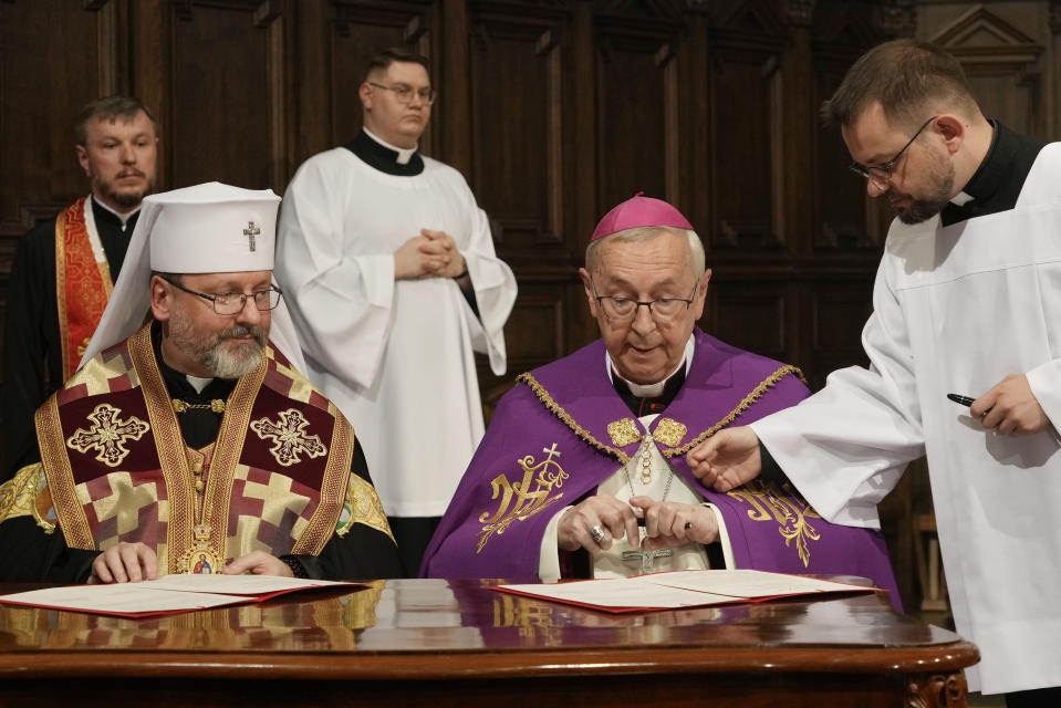 Archbishop Sviatoslav Shevchuk of the Ukrainian Greek Catholic Church, left, and the head of Poland's Roman Catholic Church, Archbishop Stanislaw Gadecki, right, exchange forgiveness and reconciliation notes during a joint religious service held as part of observances honoring some 100,000 Poles murdered by Ukrainian nationalists in 1943-44, at St. John's cathedral in Warsaw, Poland, on Friday, July 7, 2023. (AP Photo/Czarek Sokolowski)