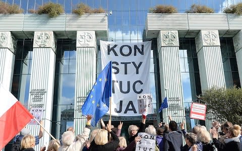 Government opponents hung signs reading "Constitution" to protest the changes to the supreme court  - Credit: AP Photo/Czarek Sokolowski