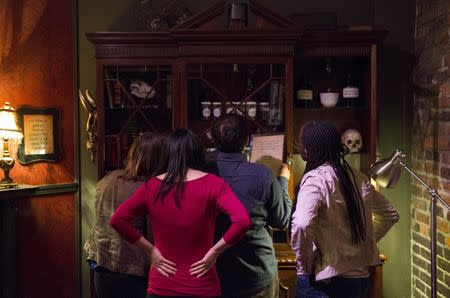 People work to find clues and solve puzzles to escape from a Sherlock Holmes-themed escape room in Alexandria, Virginia October 17, 2015. REUTERS/Joshua Roberts