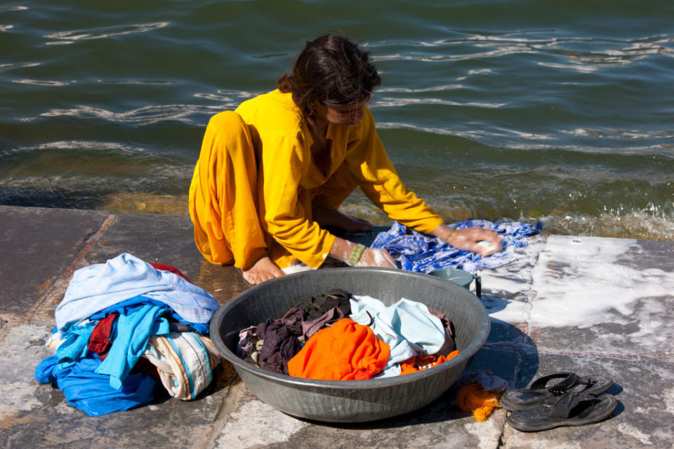 Young Indian girl squatting down to do her laundry in the waters of Lake Pichola, Udaipur, Rajasthan, Western India | Tim Graham—Getty Images