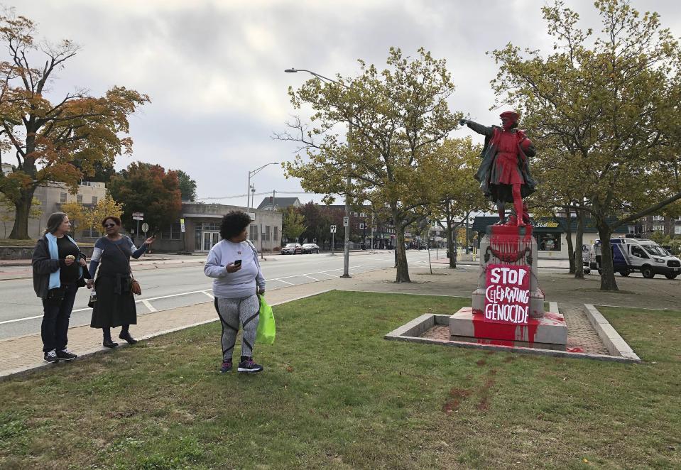 People stop to view red paint covering a statue of Christopher Columbus on Monday, Oct. 14, 2019, in Providence, R.I., after it was vandalized on the day named to honor him as one of the first Europeans to reach the New World. The statue has been the target of vandals on Columbus Day in the past. (AP Photo/Michelle R. Smith)