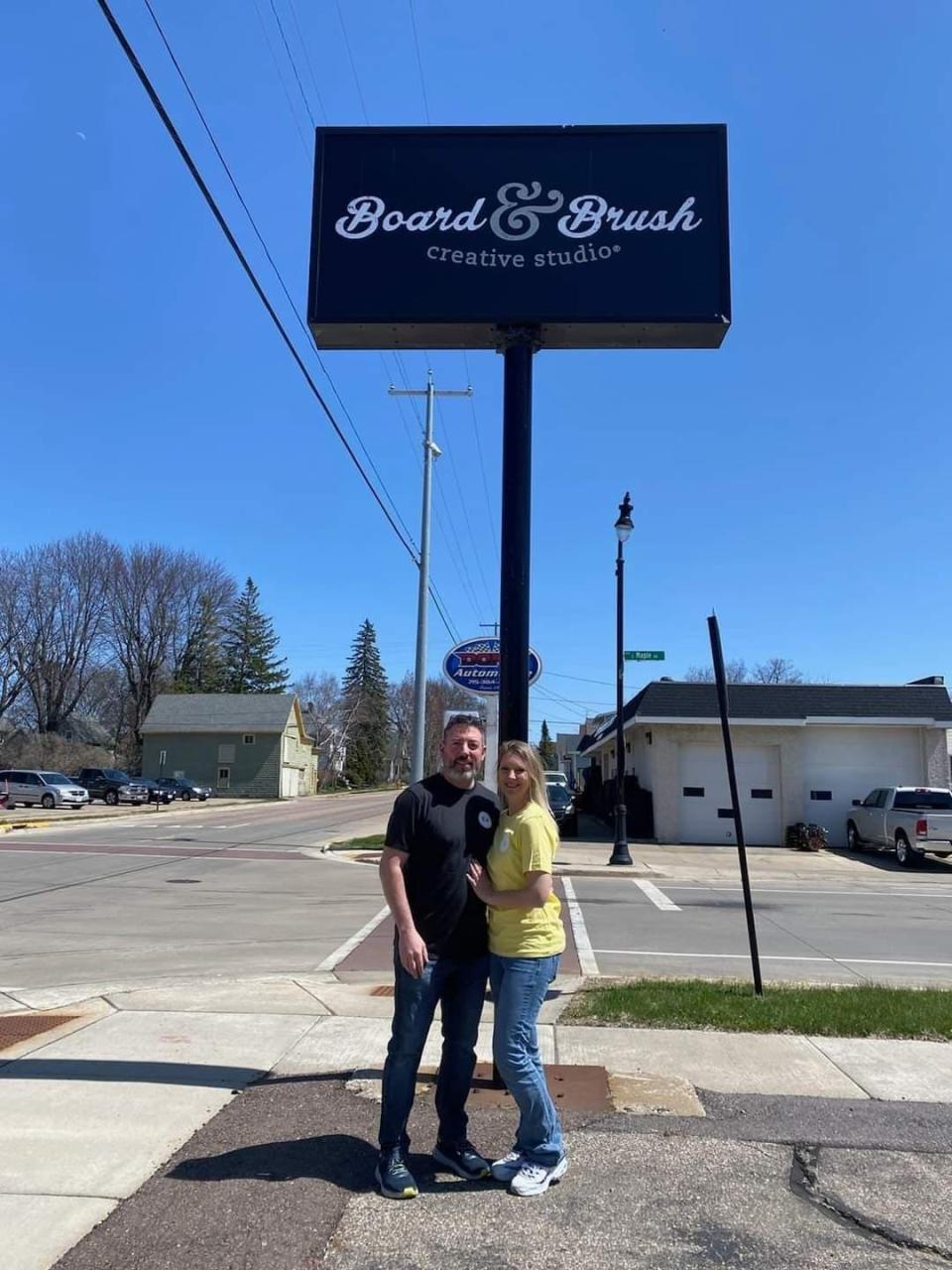 Tanya and Andy Woltmann pose in front of the Board & Brush sign outside of their studio, 112 E. Fourth St. in Marshfield.