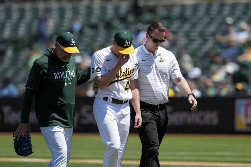 Oakland Athletics pitcher Richard Lovelady, center, walks off the field after an injury during the seventh inning of a baseball game against the Tampa Bay Rays in Oakland, Calif., Thursday, June 15, 2023. (AP Photo/Godofredo A. Vásquez)
