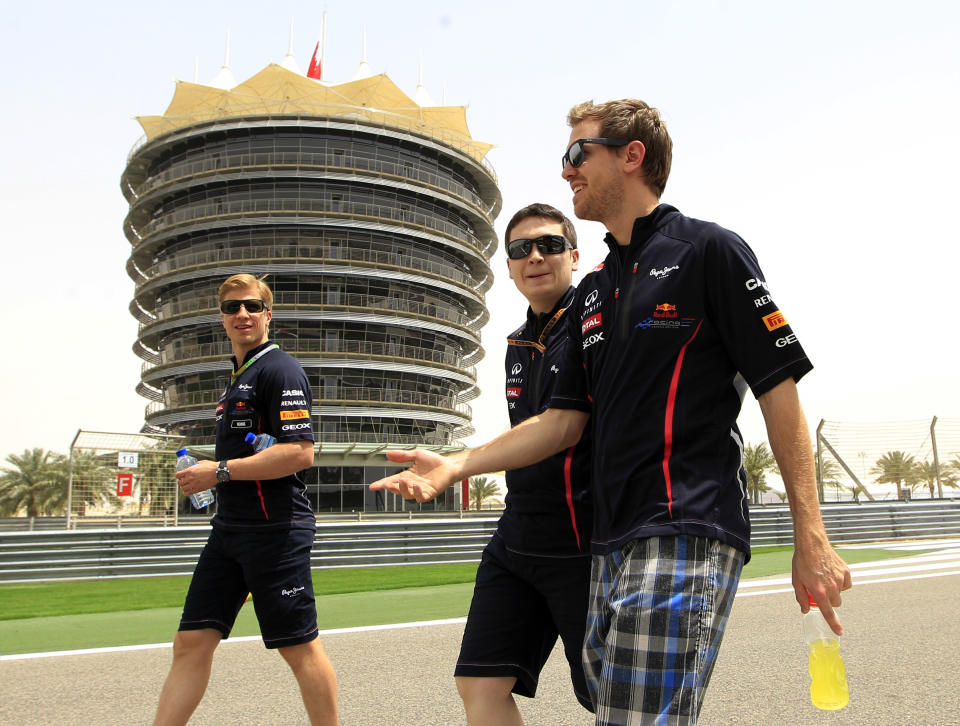 Red Bull driver Sebastian Vettel of Germany, right, walks with team technicians at the Formula One Bahrain International Circuit in Sakhir, Bahrain, Thursday, April 19, 2012. The Bahrain Grand Prix was canceled last year due to anti-government protests that have left nearly 50 dead, but last week Formula One boss Bernie Ecclestone declared the Gulf kingdom safe and decided to go ahead with this year's race. The Bahrain Formula One Grand Prix will take place here on Sunday. (AP Photo/Luca Bruno)