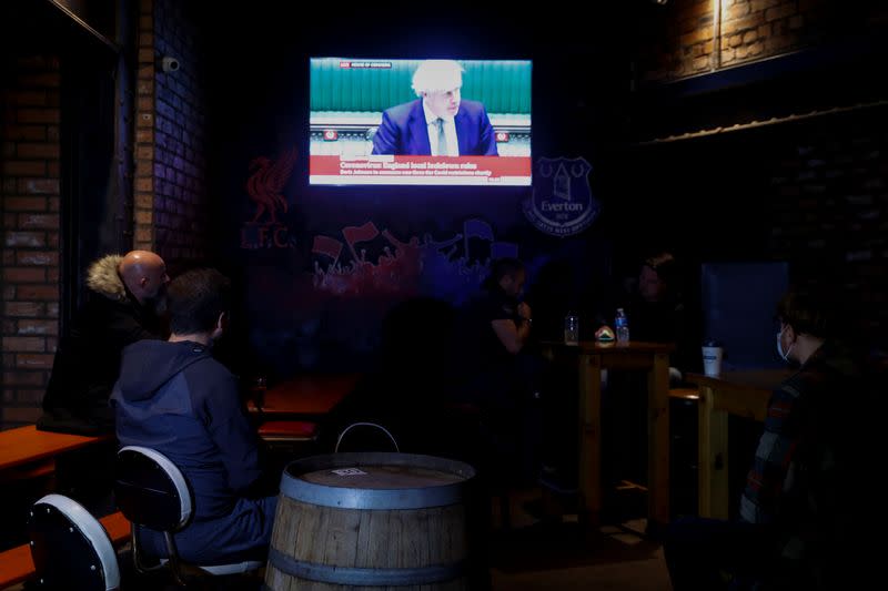 People watch Britain's Prime Minister Boris Johnson making a speech, at a pub, amid the outbreak of the coronavirus disease (COVID-19) in Liverpool