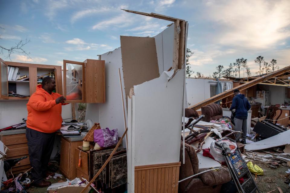 Granadas Baker, left, and son Granadas Jr. 18, right, retrieve personal items from the damaged home where they survived a tornado a day earlier in Beauregard, Ala., Monday, March 4, 2019.