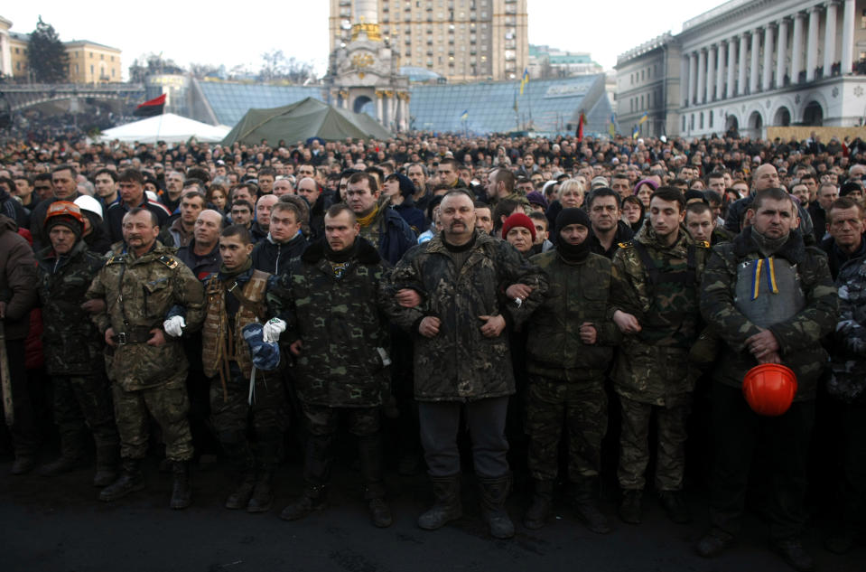 People gather at Independence Square during a funeral procession for anti-government protesters killed in clashes with the police in Kiev, Ukraine, Friday, Feb. 21, 2014. In a day that could significantly shift Ukraine’s political destiny, opposition leaders signed a deal Friday with the country’s beleaguered president that calls for early elections, a new constitution and a new unity government. (AP Photo/ Marko Drobnjakovic)