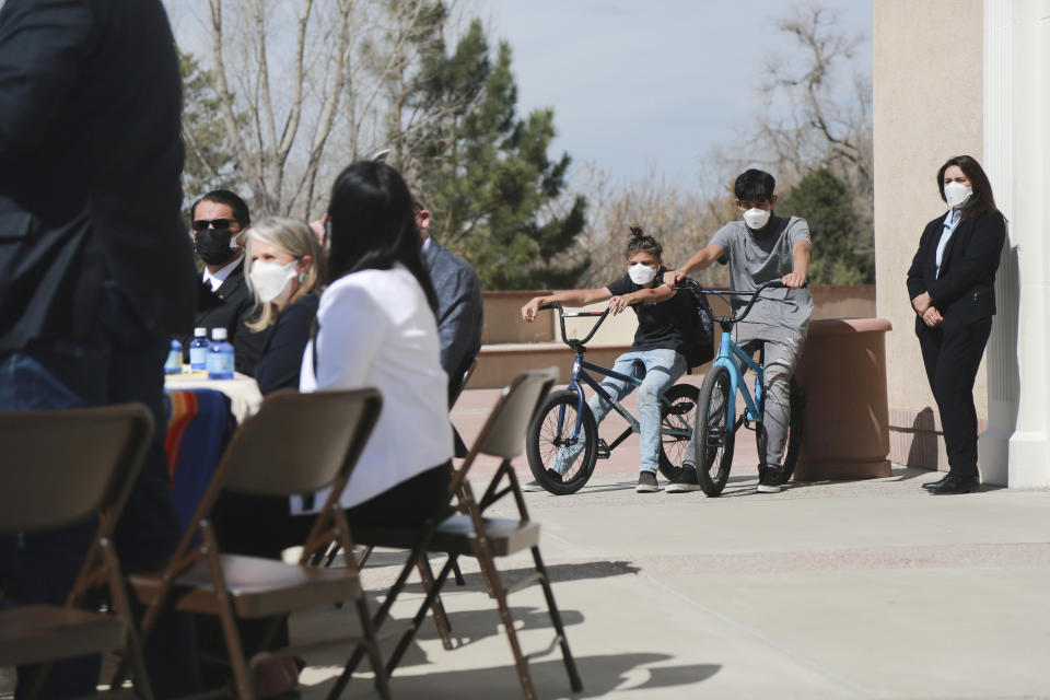 In this Monday, April 5, 2021, photo Jonathan Chilton, 14, center, sits on his BMX bike in front of the New Mexico state capitol ahead of a bill signing by the governor in Santa Fe, N.M. Chilton started school remotely on Tuesday following the Easter break. Around half of his classmates are now studying in-person, and he's not sure if he should go back with just a few weeks left in the semester. (AP Photo/Cedar Attanasio)