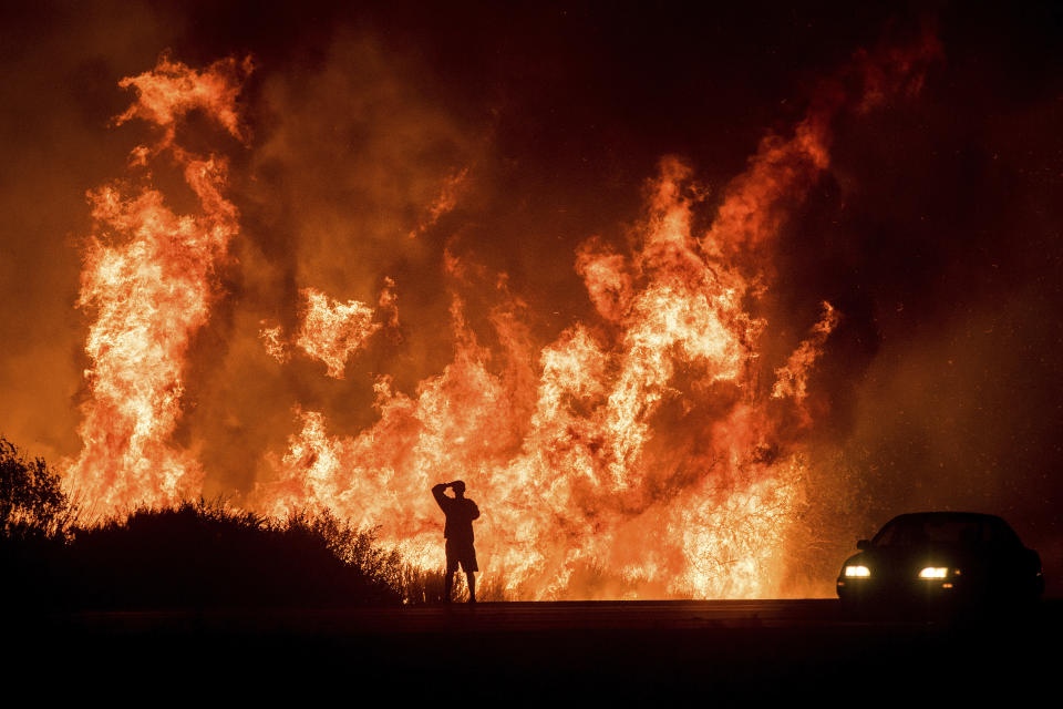 FILE - A motorists on Highway 101 watches flames from the Thomas Fire leap above the roadway north of Ventura, Calif., on Dec. 6, 2017. Southern California Edison will pay $80 million to settle claims connected to a massive wildfire that destroyed more than a thousand homes and other structures in 2017, federal prosecutors said Monday, Feb. 26, 2024. (AP Photo/Noah Berger, File)