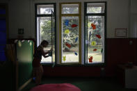 A worker cleans a window in the 'La Giostra Nel Parco' (Merry go around in the park) nursery school in Milan, northern Italy, Thursday, Aug. 27, 2020, ahead of reopening. Despite a spike in coronavirus infections, authorities in Europe are determined to send children back to school. Italy, Europe’s first virus hot spot, is hiring 40,000 more temporary teachers and ordering extra desks, but some won’t be ready until October. (AP Photo/Luca Bruno)