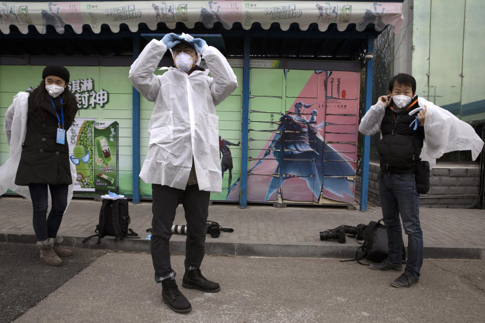In this Thursday, Feb. 27, 2020, photo, journalists put on protective overalls before entering the Mengniu dairy factory in Beijing. Reporters were invited to China Mengniu Dairy Co. Ltd. this week to be shown how companies are reviving after anti-virus measures shut down most of the world's second-biggest economy. (AP Photo/Ng Han Guan)