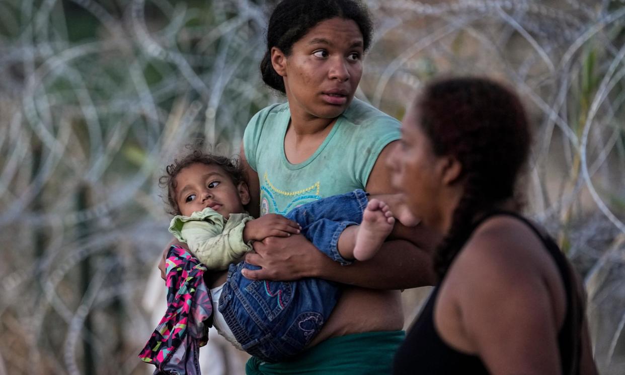 <span>A woman carries her child after she and other migrants crossed the Rio Grande into the US. The image was part of a series by Associated Press photographers that won the 2024 Pulitzer prize for feature photography.</span><span>Photograph: Eric Gay/AP</span>