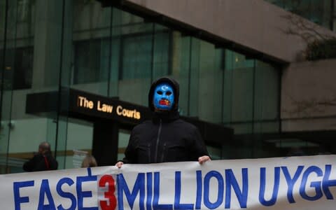 A protester against China's imprisonment of Uighur people outside the courtroom on Jan 20,. His face is painted with the blue and white flag of East Turkestan, a symbol of Uighur nationalism, and he holds up a banner referencing Chinese detention camps - Credit: Mert Alper Dervis/Getty/Anadolu