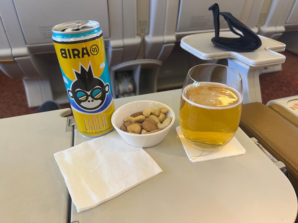 Beer and nuts on a tray table.
