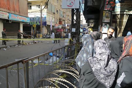 Residents stand next to barbed wire as Lebanese army soldiers secure the area at the site of the two explosions that occured on Thursday in the southern suburbs of the Lebanese capital Beirut, November 13, 2015. REUTERS/Aziz Taher