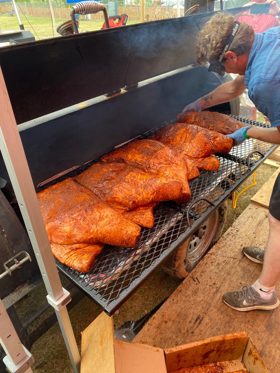 Marshall Bartlett, owner of Home Place Pastures and member of the Sweet Cheeks BBQ Competition Barbecue Team, puts shoulders on the smoker at the 2023 Memphis in May World Championship Barbecue Cooking Contest.  Memphis-based Sweet Cheeks BBQ placed first in the Shoulder division.