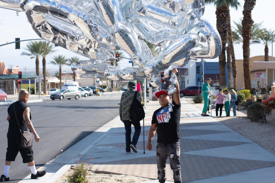 A street vendor holds up balloons as part of artist Hector Zamora's Desert X installation "Chimera" near Desert Hot Springs City Hall in Desert Hot Springs, Calif., on March 3, 2023.