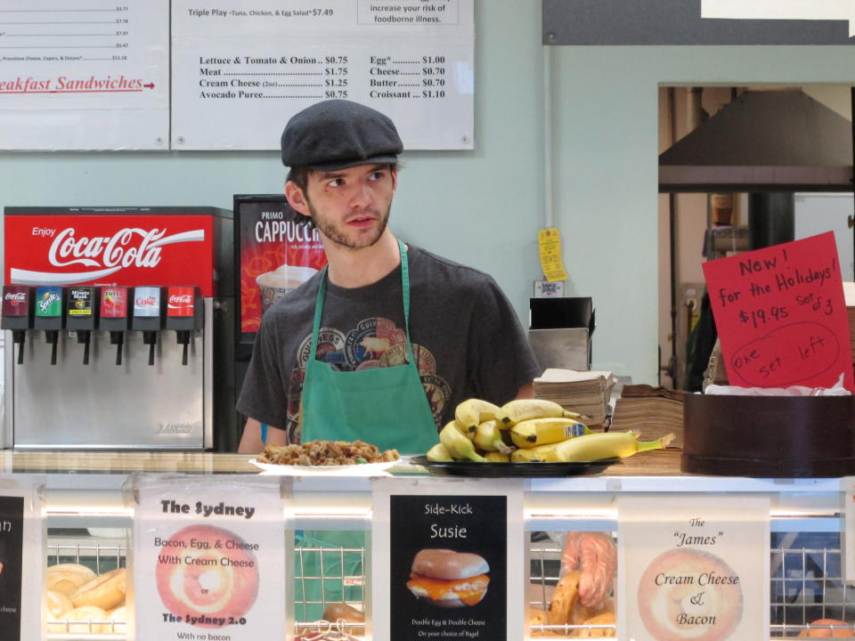 In this Monday, Jan. 27, 2014 photo, Neal Breen, 21, works at the Ashburn Bagel & Sandwich Shop in Ashburn, Va. Breen, who quit college a year earlier with hopes of saving money to start his own business, is keenly aware that the wealth in the neighborhoods where he delivers breakfast sandwiches is, for now, beyond reach. But he does not decry the gap between the Vienna sausage dinners of childhood and the $168,000 median income of the households surrounding this shopping center, about 35 miles from Capitol Hill. It just confirms that the free-market economy is working, he says, by rewarding those who do for themselves. (AP Photo/Adam Geller)