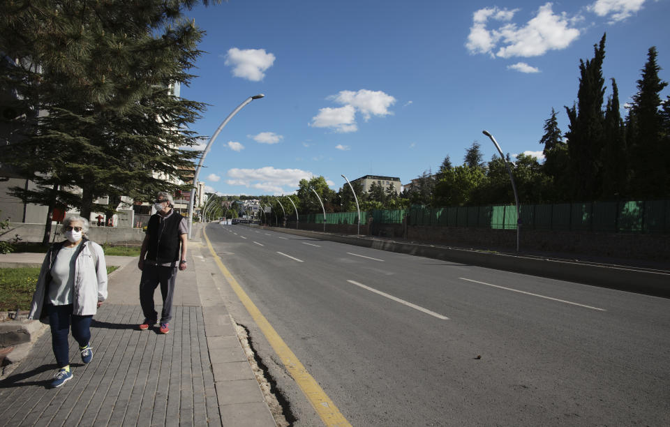 Elderly people wearing face masks for protection against the coronavirus, walk along the main Ataturk Boulevard in Ankara, Turkey, Sunday, May 24, 2020, during a four-day curfew declared by the government in an attempt to control the spread of coronavirus. Turkey's senior citizens were allowed to leave their homes for a third time as the country continues to ease some coronavirus restrictions. (AP Photo/Burhan Ozbilici)
